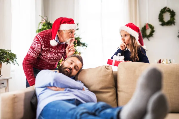 Una bambina con il nonno non vuole svegliare il padre addormentato a Natale. . — Foto Stock