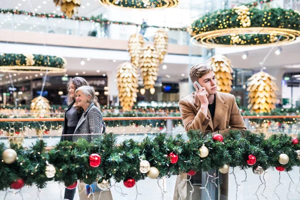 A portrait of teenage boy with smartphone in shopping center at Christmas. — Stock Photo, Image