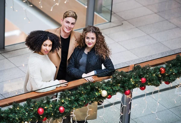 Jovens amigos em pé no centro comercial na época do Natal . — Fotografia de Stock