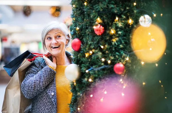 Ritratto di donna anziana con sacchetti di carta nel centro commerciale a Natale . — Foto Stock