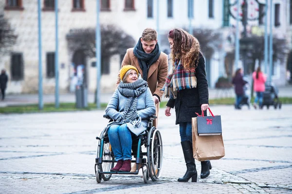 青少年和高级祖母在轮椅上漫步在冬天的街道上. — 图库照片