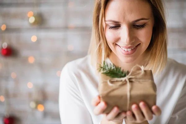 Une jeune femme tenant un cadeau de Noël enveloppé . — Photo