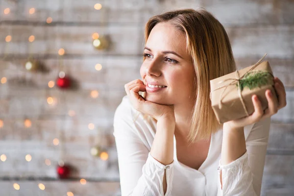 Une jeune femme tenant un cadeau de Noël enveloppé . — Photo