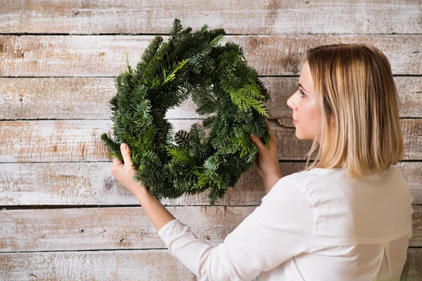 Une jeune femme tenant une couronne de Noël verte . — Photo