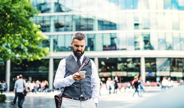 Hipster hombre de negocios con smartphone de pie en la calle en la ciudad . —  Fotos de Stock