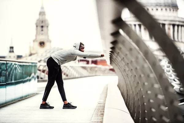 Uomo nero corridore sul ponte in una città, che si estende . — Foto Stock