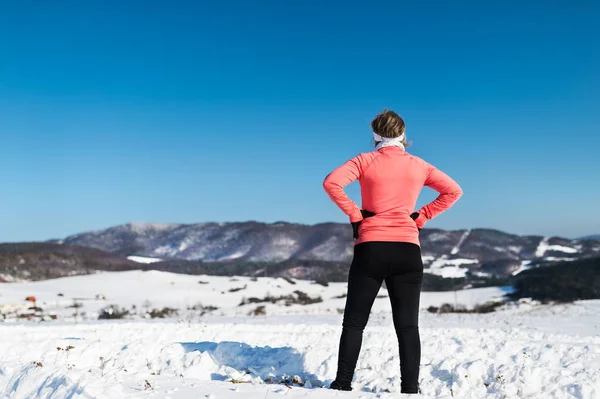 Pohled zezadu na běžec starší žena odpočívá v zimní přírodě. — Stock fotografie