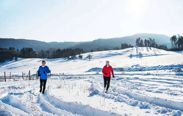 雪に覆われた冬の自然にジョギング シニア カップルのフロント ビュー. — ストック写真