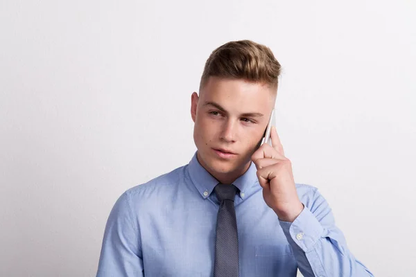 Portrait of a young man with smartphone in a studio, making a phone call. — Stock Photo, Image