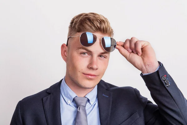 Портрет уверенного молодого человека в солнечных очках в студии, в костюме и галстуке . — стоковое фото
