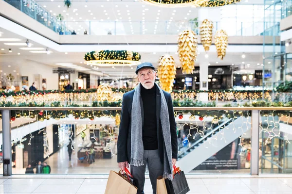 Ένας ανώτερος άνθρωπος βαρεθεί και κουραστεί με χάρτινες τσάντες σε εμπορικό κέντρο στο χρόνο Χριστουγέννων. — Φωτογραφία Αρχείου