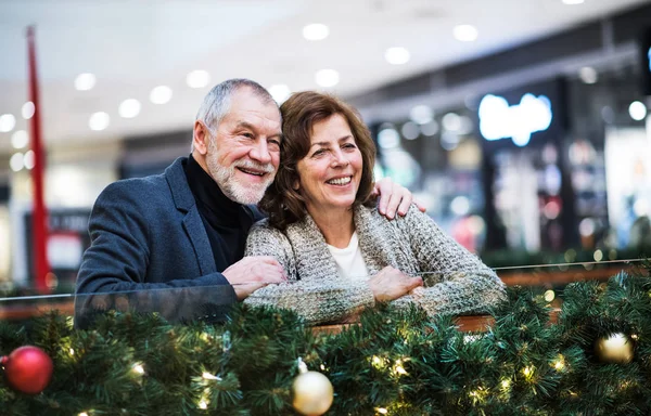 Een portret van senior paar in shopping center op Kerstmis. — Stockfoto