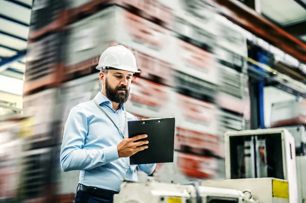 Ett porträtt av ingenjör industriell mannen med Urklipp i en fabrik, arbetar. — Stockfoto