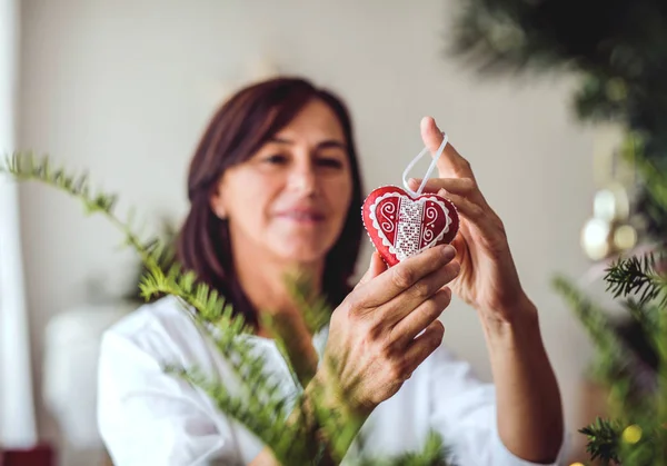 Seniorin schmückt zu Hause einen Weihnachtsbaum. — Stockfoto