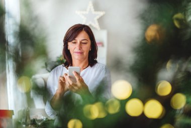Smartphone vasıl evde zaman Noel üst düzey bir kadınla. Kopya alanı.