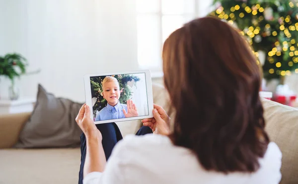 Mujer mayor con tableta hablando con su nieto a través de videollamada en línea . — Foto de Stock