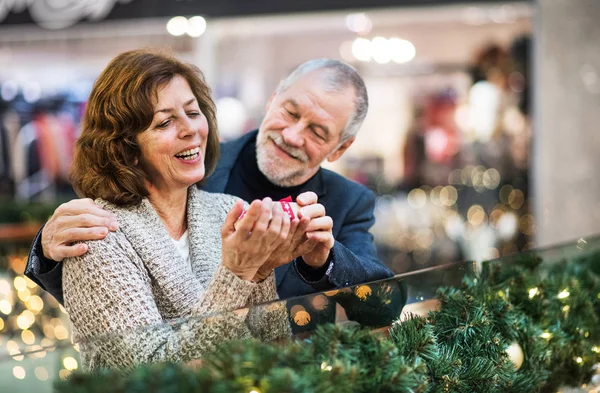 Ritratto di coppia anziana con un regalo nel centro commerciale nel periodo natalizio . — Foto Stock