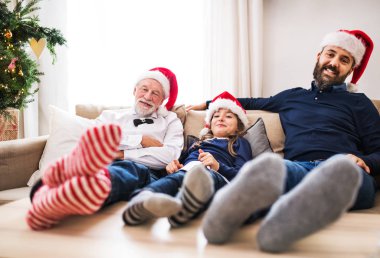 Babası ve dedesi Noel zamanda kanepede oturan küçük bir kızla.
