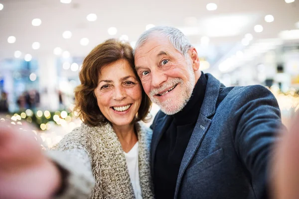 Casal sênior tirando selfie no centro comercial na época do Natal . — Fotografia de Stock