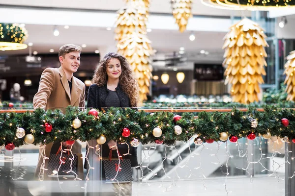 Een jong koppel staande in winkelcentrum met Kerstmis. Kopiëren van ruimte. — Stockfoto