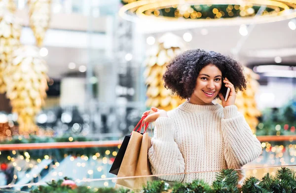 Portret nastolatkę z smartphone i papieru torby w centrum handlowym na Boże Narodzenie. — Zdjęcie stockowe
