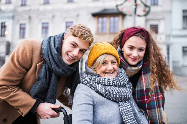 Teenager und Großmutter im Rollstuhl im Winter auf der Straße. — Stockfoto