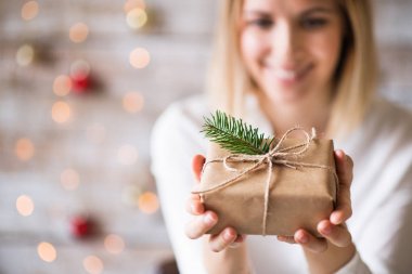 Tutan bir genç kadın Noel hediyesi sarılmış.