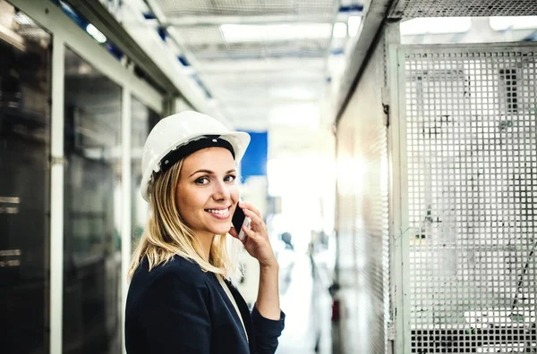 Sebuah potret seorang insinyur wanita industri di telepon, berdiri di sebuah pabrik . — Stok Foto