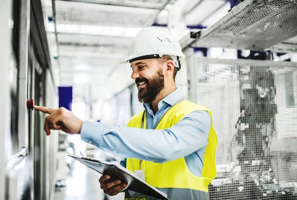 Un retrato de un ingeniero industrial con portapapeles en una fábrica, trabajando . — Foto de Stock