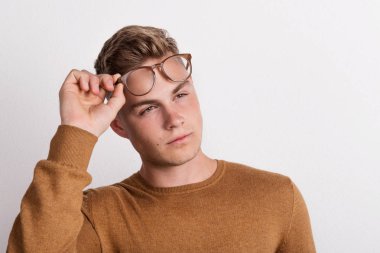 Gözlük alnına tutarak kendine güvenen genç bir adam bir stüdyoda.