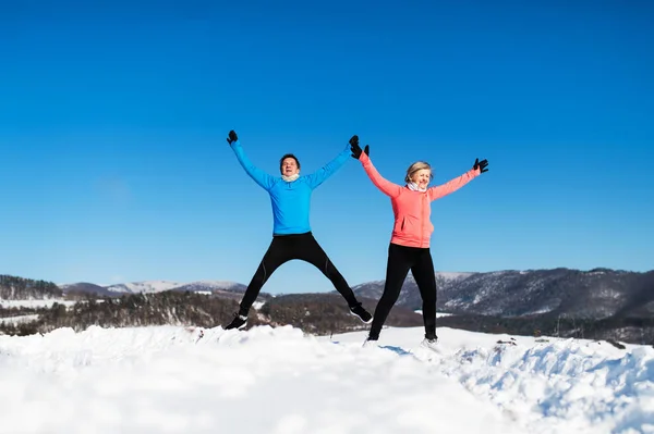 Glückliche Senioren-Paarläufer springen in winterlicher Natur. — Stockfoto