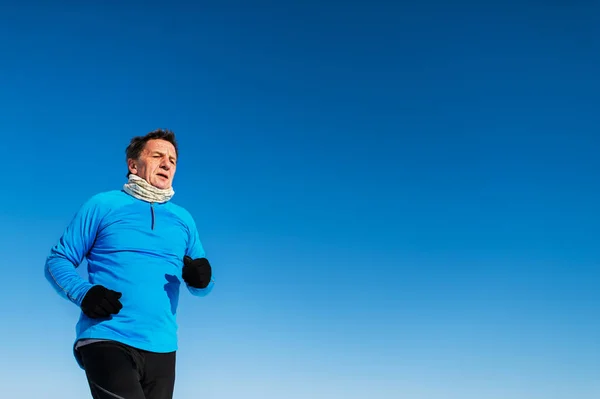 Senior man jogging in winter nature. Copy space. — Stock Photo, Image