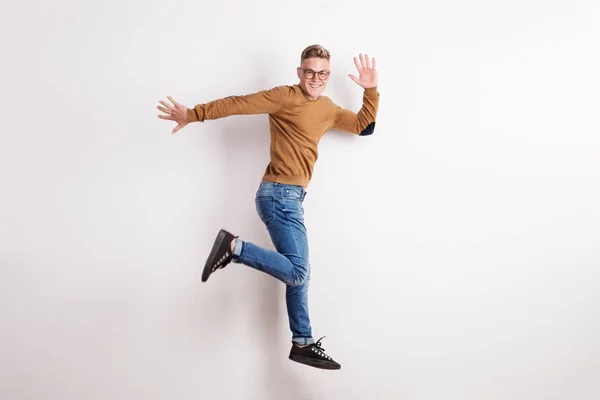 Retrato de um jovem feliz em um estúdio, pulando . — Fotografia de Stock
