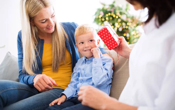 En mor och mormor ger presentera en liten pojke hemma i juletid. — Stockfoto