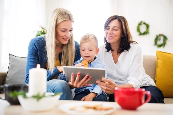 Egy kisfiú, anyja és nagyanyja otthon karácsonykor, tablet használata. — Stock Fotó