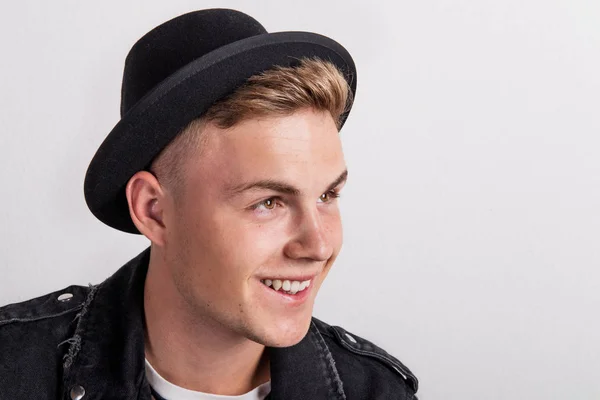 Close-up portrait of a confident young man with a black hat in a studio. — Stock Photo, Image