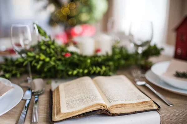 Boek van de Bijbel op een tabel die is ingesteld voor een diner thuis bij Kerstmis. — Stockfoto