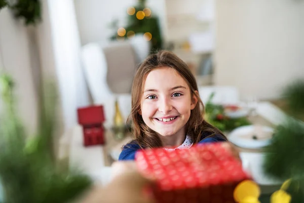 Une petite fille avec un cadeau à la maison à la période de Noël . — Photo