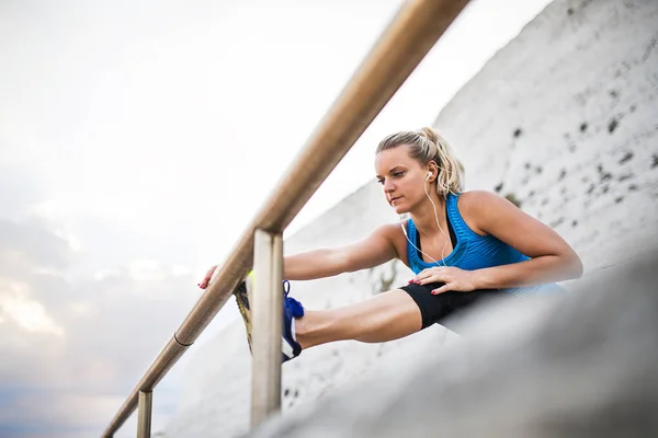 Genç sportif kadın runner kulaklık dışında sahilde uzanan ile. — Stok fotoğraf