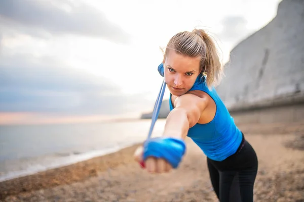 Genç sportif kadın runner bir plajda dışında lastikleri ile egzersiz. — Stok fotoğraf