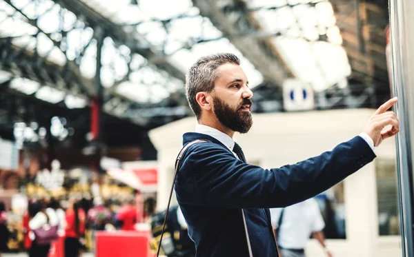 Empresário Hipster em pé na estação de ônibus ou trem, verificando o horário . — Fotografia de Stock