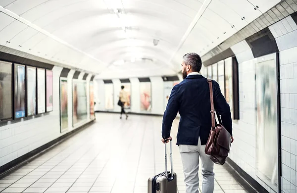 Pohled zezadu na podnikatele s vakem a kufr chůzi v metru. — Stock fotografie