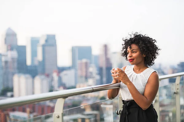 Ritratto di una donna in piedi su una terrazza con in mano una tazza di caffè . — Foto Stock