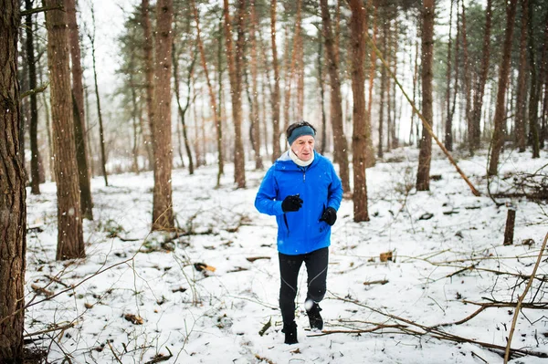 Starszy człowiek jogging w lesie w zimie przyrodzie. — Zdjęcie stockowe