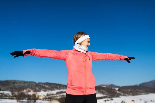 Senior Kvinna löpare stretching i vinter natur. Kopiera utrymme. — Stockfoto