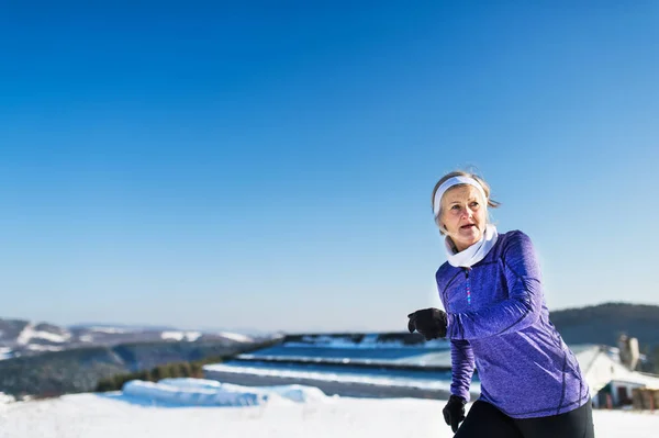 Senior Kvinna jogging i vinter natur. Kopiera utrymme. — Stockfoto