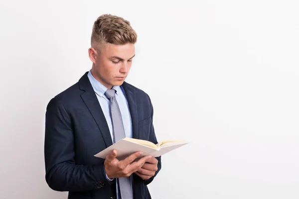 Retrato de un joven en un estudio, sosteniendo y leyendo un libro . —  Fotos de Stock