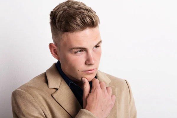 Portrait of serious young man in a studio, wearing brown coat. Copy space. — Stock Photo, Image