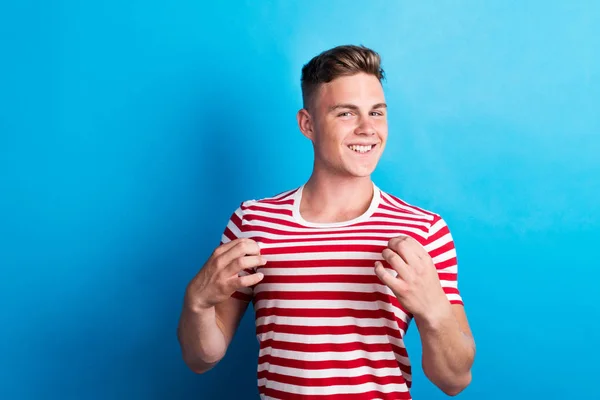 En ung man i en studio, klädd i randig röd och vit T-shirt. — Stockfoto