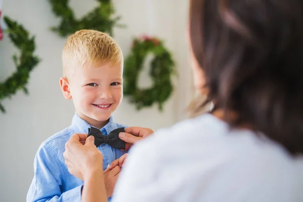 Una abuela poniéndole una corbata a un niño pequeño en Navidad . — Foto de Stock